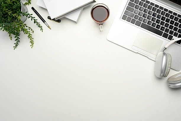 Minimalistiskt skrivbord med laptop, hörlurar, anteckningar och kaffe